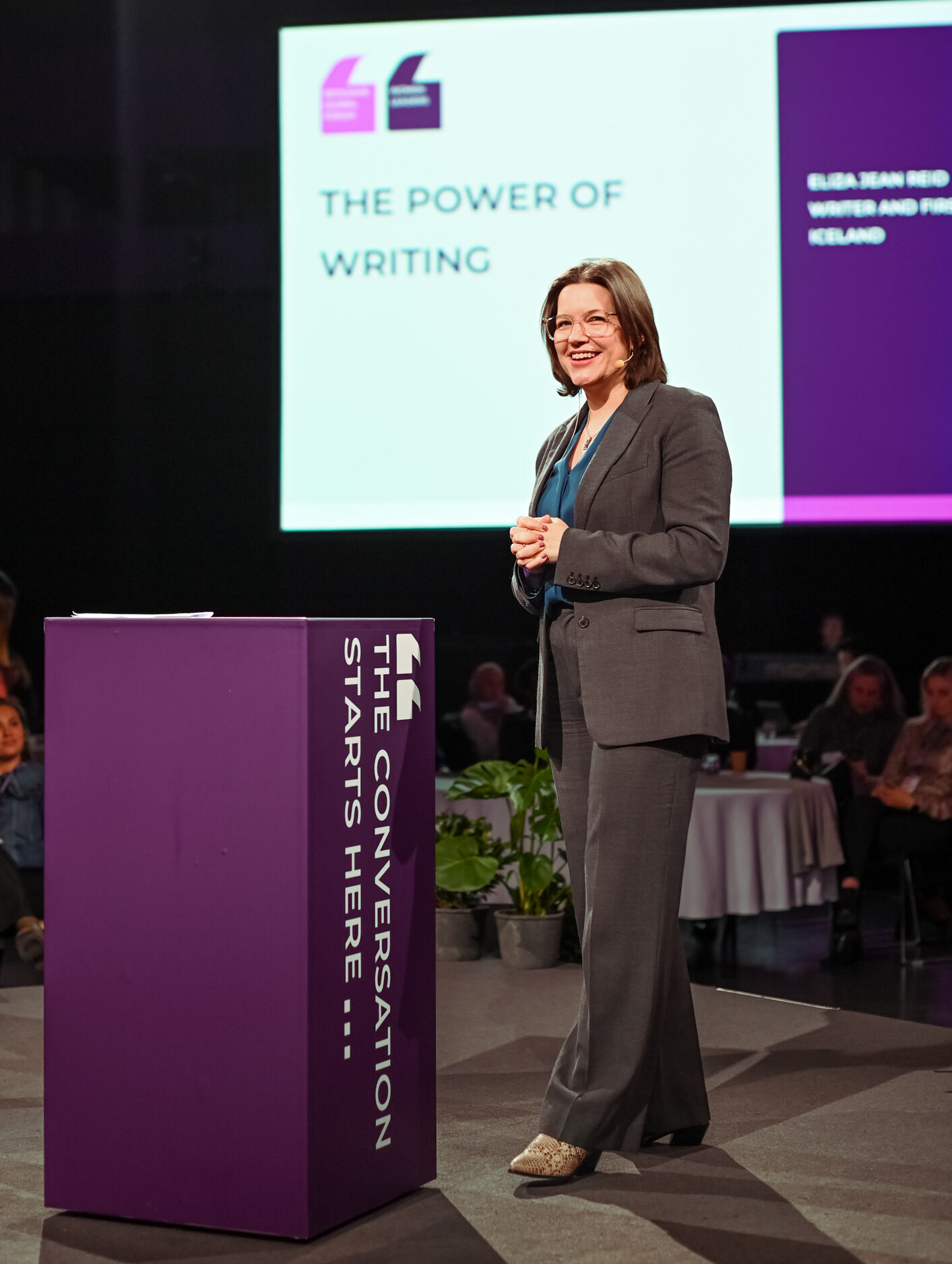 Eliza Reid speaking on stage with a headset microphone
